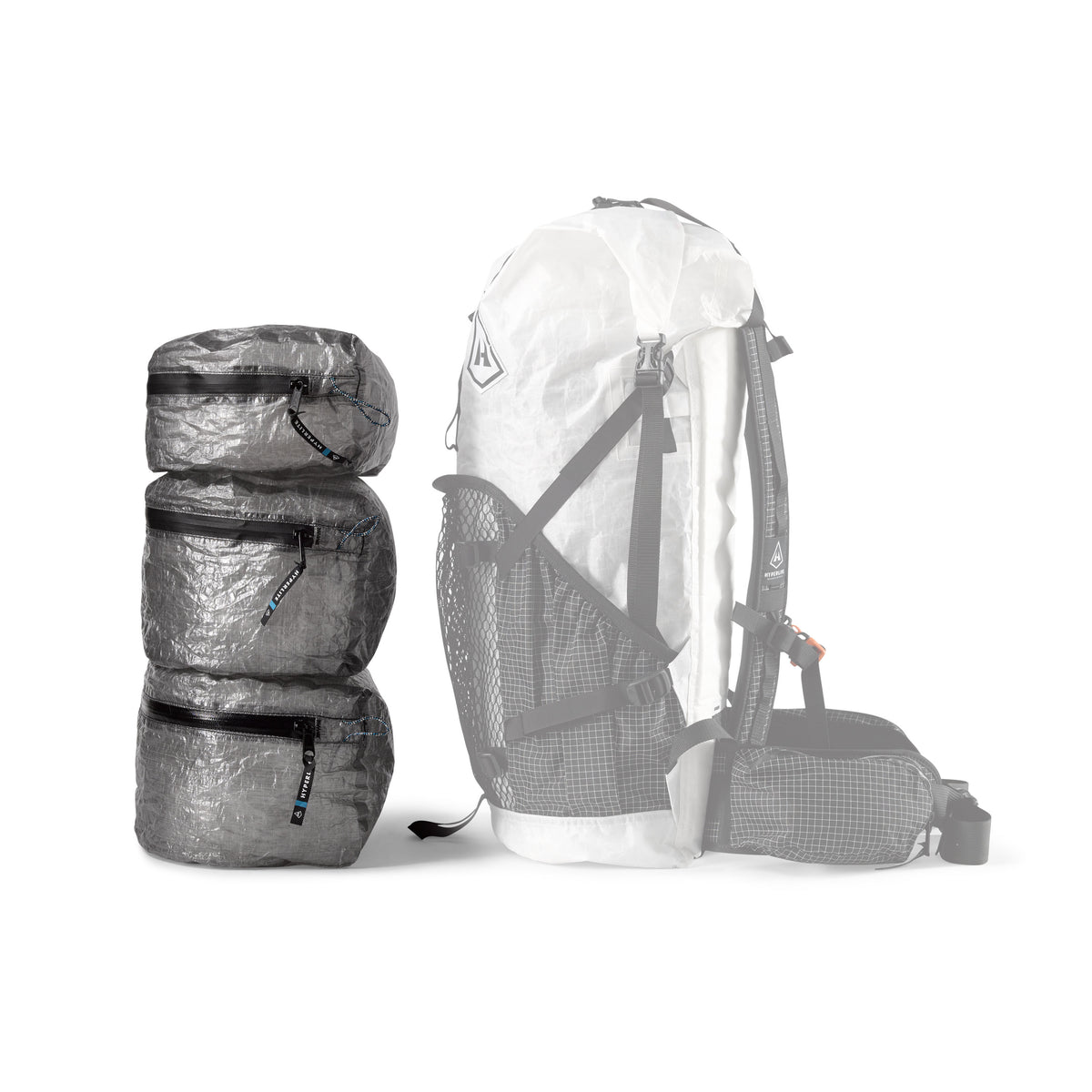 Three different sizes of the Hyperlite Mountain Gear Pods placed next to a pack for a size comparison