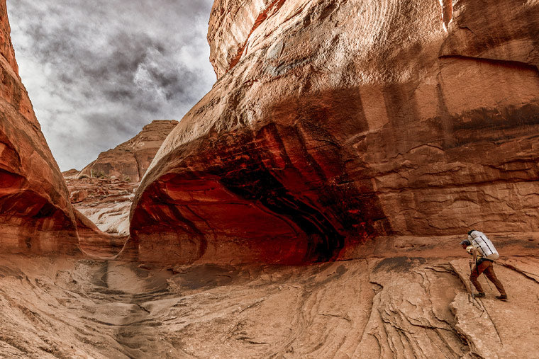 Person hiking through a canyon with large rock formations.