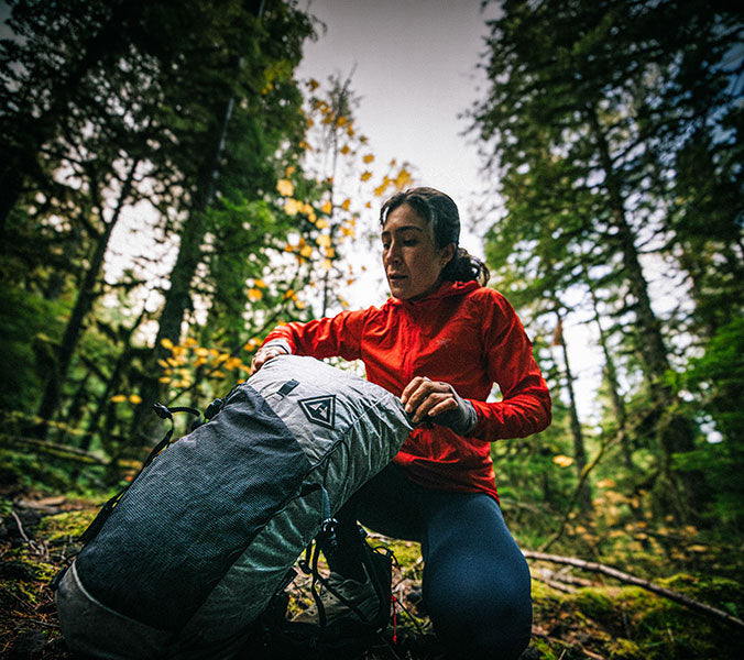 Person in red jacket with gray Hyperlite Mountain Gear backpack in forest