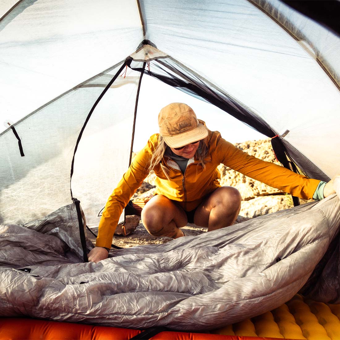 Person setting up a camping tent in a natural outdoor setting