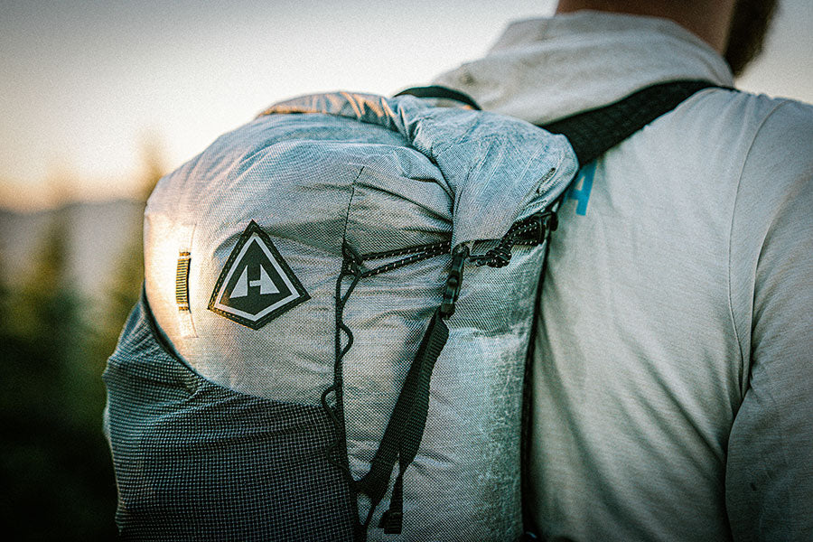 Person wearing a backpack with a visible Hyperlite Mountain Gear logo against a natural background