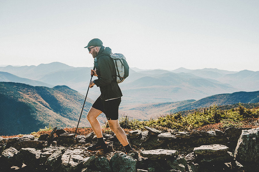 Man hiking on a rocky mountain trail with mountains in the background