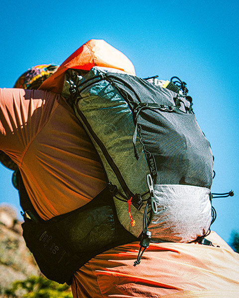 Person wearing a large backpack with a clear blue sky in the background