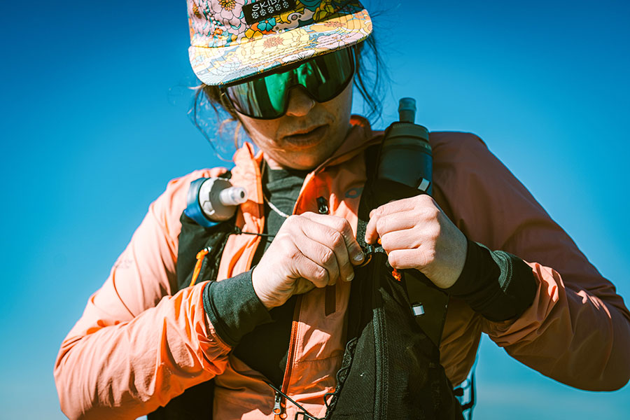 Person adjusting gear against a clear blue sky