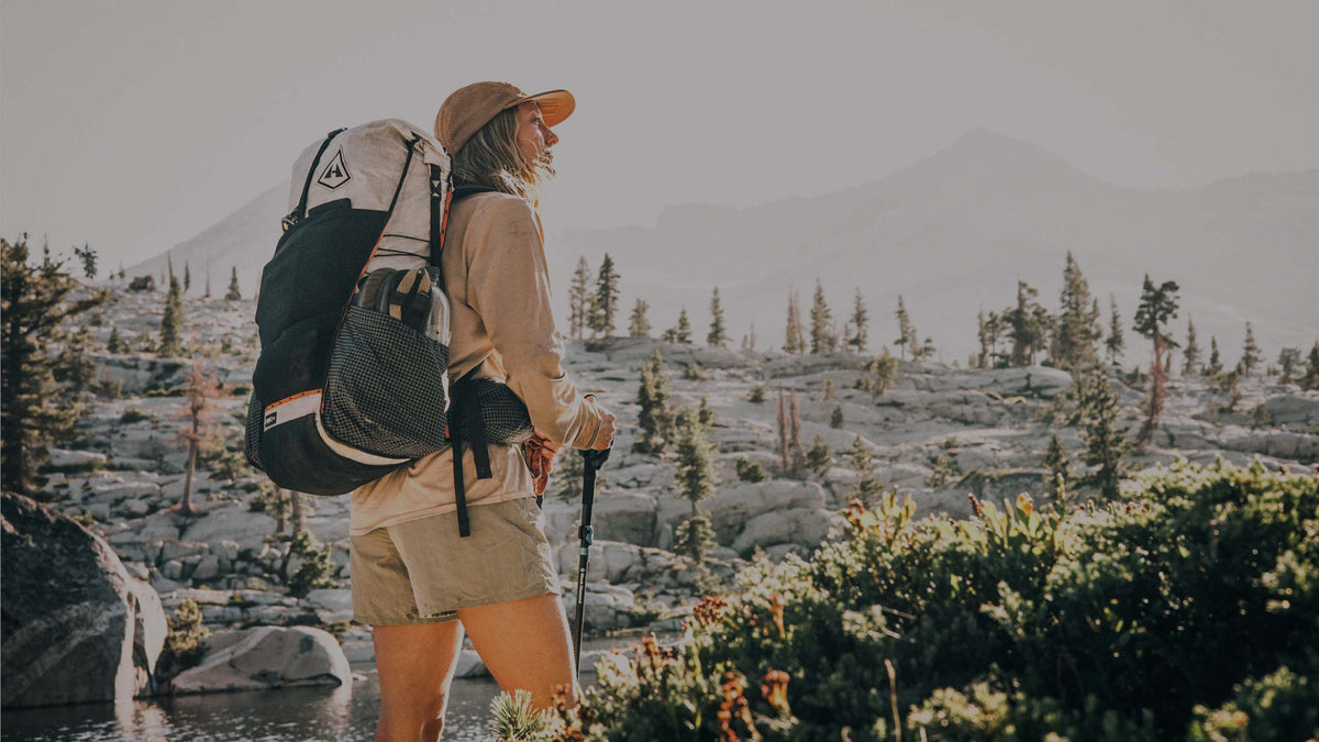 Person hiking in a mountainous landscape with backpack and walking stick