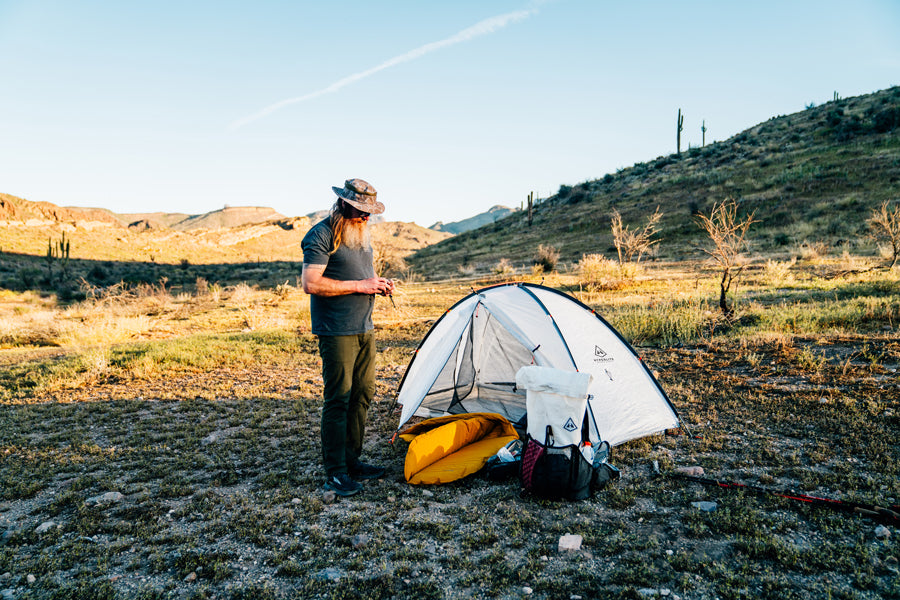Person setting up a tent in a desert landscape