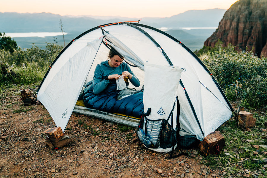 Person inside a white camping tent with a scenic background