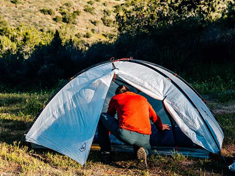 Person setting up a tent in a natural outdoor setting