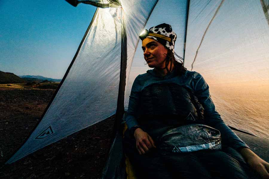 Person sitting inside a tent with a scenic background