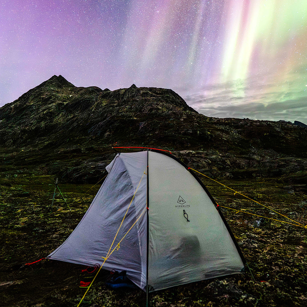 Hyperlite tent under a starry sky with aurora lights over mountains