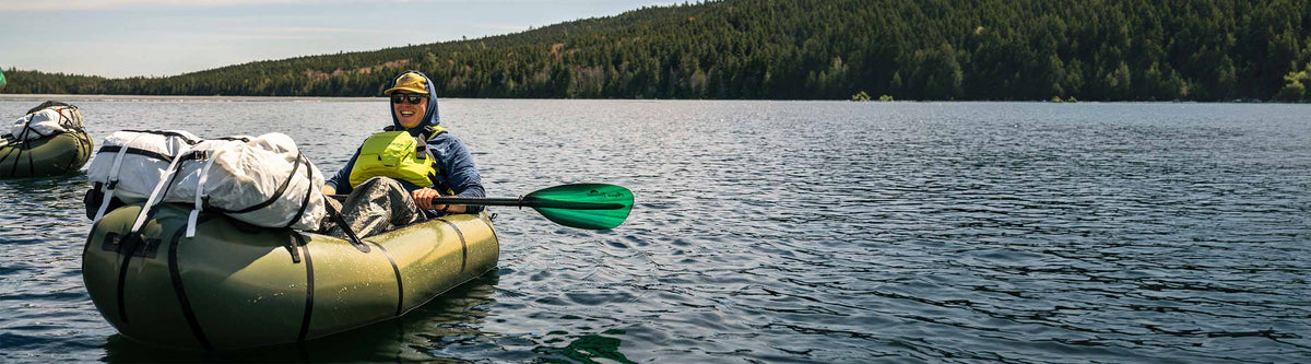 Person in a kayak on a lake with trees in the background