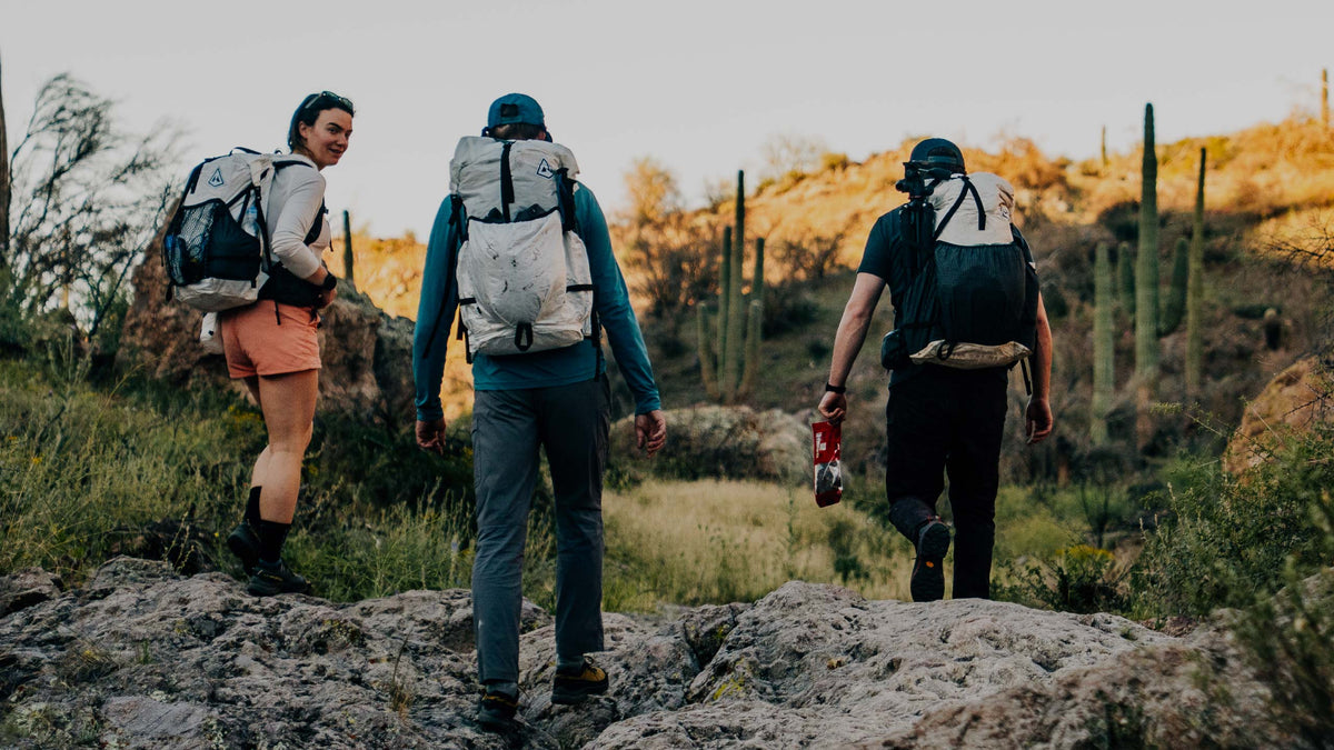 Three people hiking on a rocky trail with backpacks