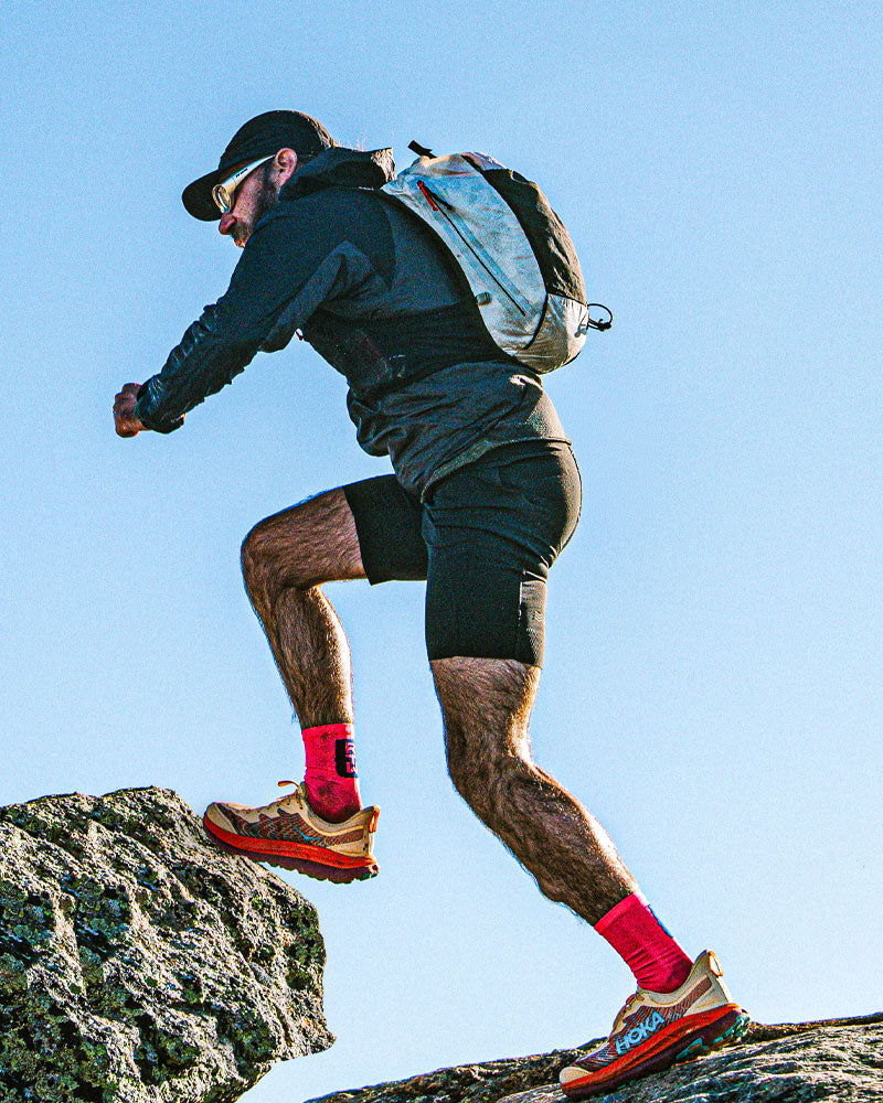 Jimmy Riopel hiking on a rocky trail with a clear blue sky and the Pemi 15 running vest