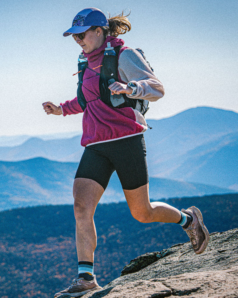 Mikaella Sansoucie running on a mountain with the Pemi 15 pack and scenic background