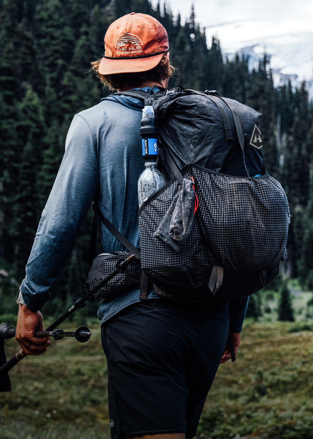 Person hiking with a black Southwest backpack and camping gear in a forest