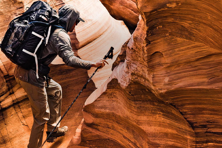 Hiker with backpack and walking poles exploring a slot canyon.