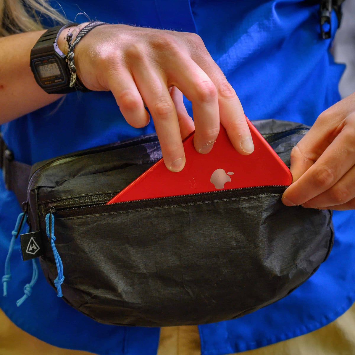 Front view of a person putting a cell phone in Hyperlite Mountain Gear's Versa in Black