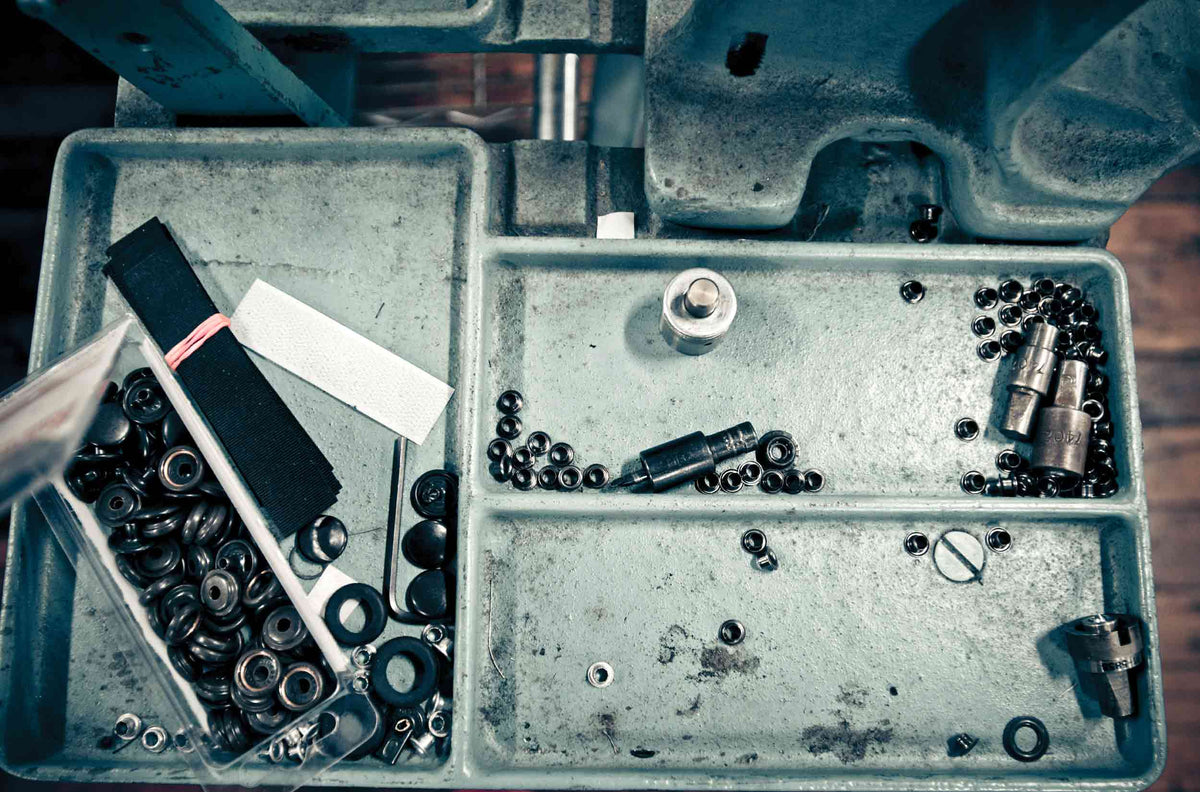 Tool box with various mechanical parts and tools on a wooden surface