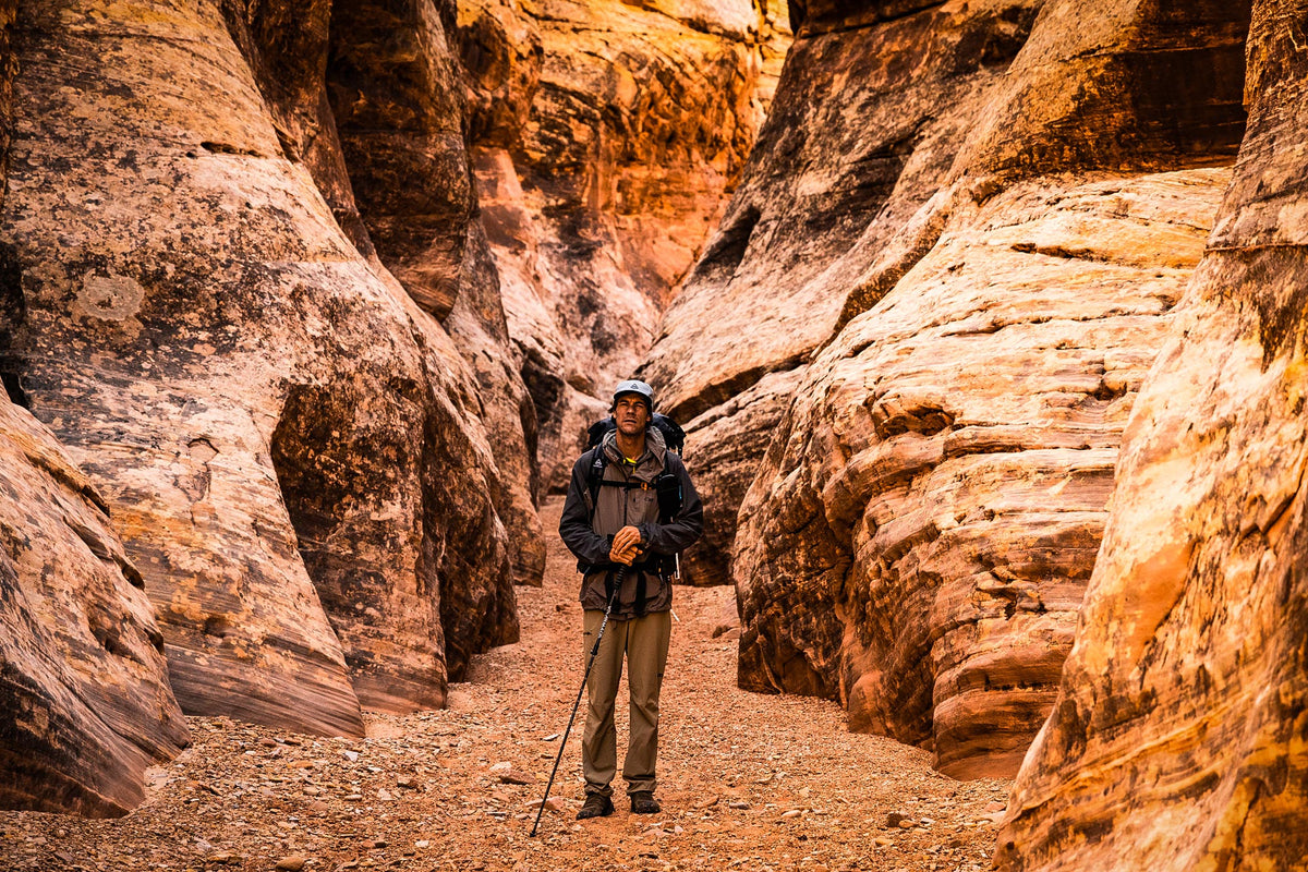 Person standing in a narrow canyon with rocky walls.